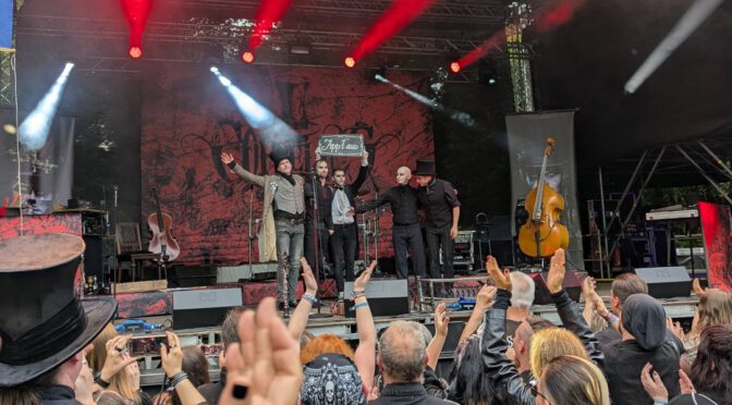 Coppelius im heidnischen Dorf beim Wave Gotik Treffen 2025 mit Applaus Schild